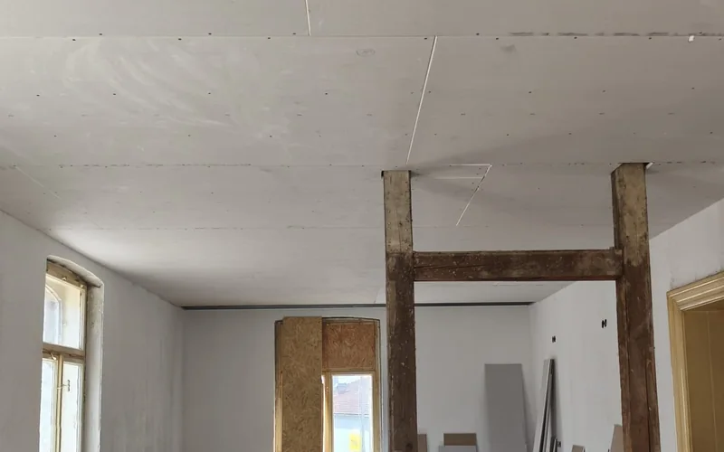 Altbau-Innenausbau: frisch beplankte Decke, freigelegtes Fachwerk und gestapelte Gipsplatten